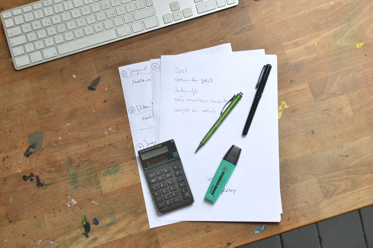 Tastatur, Taschenrechner und handschriftliche Kostenübersicht auf einem Schreibtisch